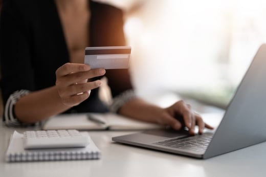 Woman holding credit card and using laptop computer. 