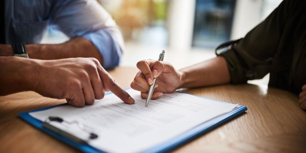 Person signing a contract with a financial advisor.