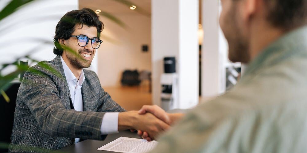 Financial advisor smiling and shaking hands with a client.