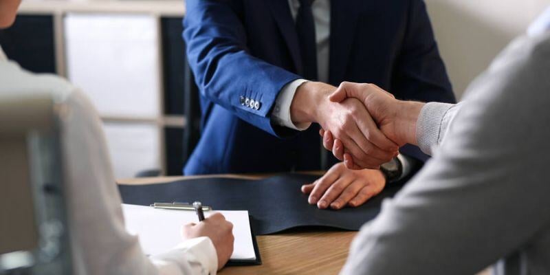 Tax advisor in a blue suit shaking hands with a client.